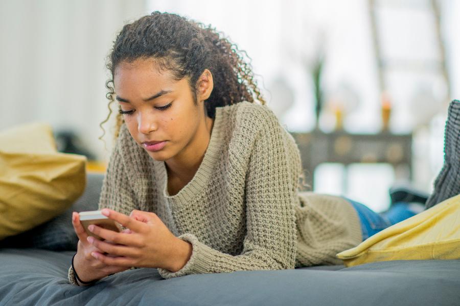 Teenager on a bed playing with her phone